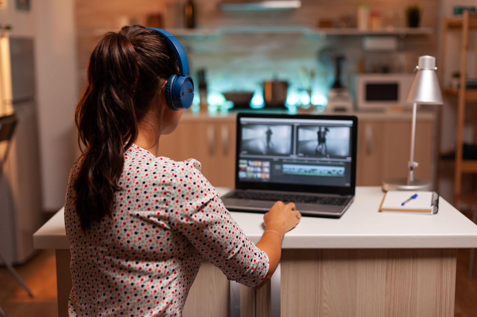 Editor sits at computer with headphones